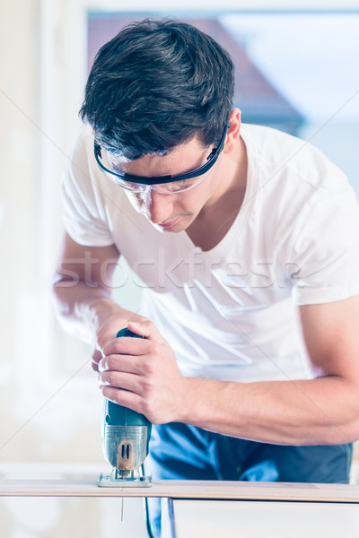 Stock photo: DIY worker cutting wooden panel with jig saw
