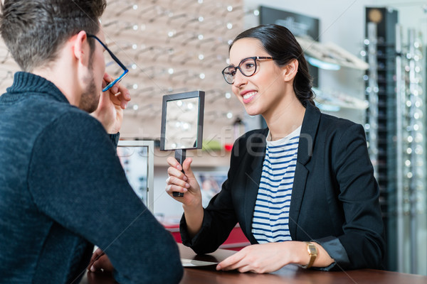 Man in optician shop getting advice from saleswoman Stock photo © Kzenon