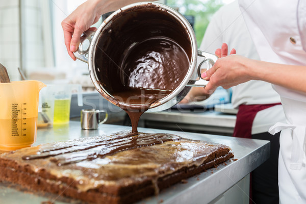 Confectioner putting chocolate as frosting on cake Stock photo © Kzenon