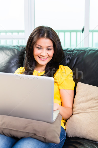 Asian woman using laptop on couch Stock photo © Kzenon