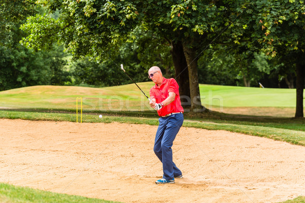 Senior man at golf having stroke in sand bunker Stock photo © Kzenon