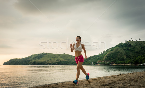 Fit young woman running on the beach during summer vacation in F Stock photo © Kzenon