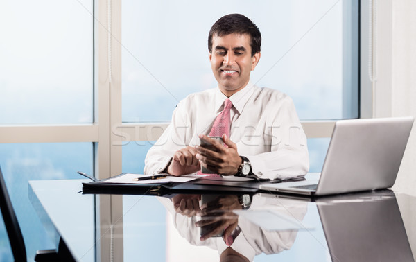 Senior manager in skyscraper office checking smart phone Stock photo © Kzenon