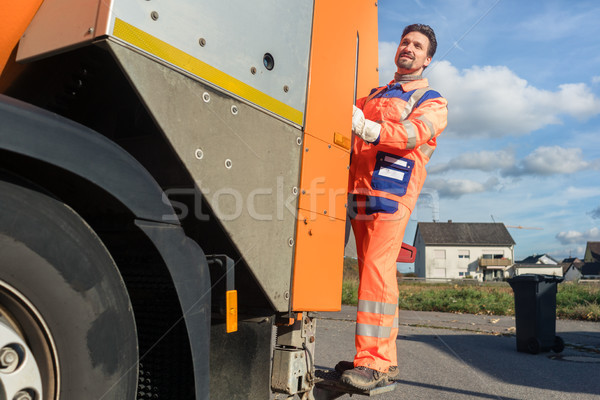 Garbage removal worker riding on the back of the disposal vehicle Stock photo © Kzenon