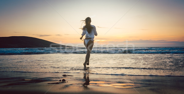 Woman at the beach in sunset entering the water Stock photo © Kzenon