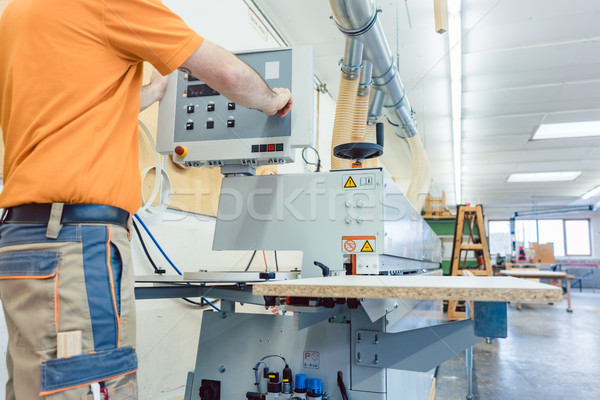 Carpenter in furniture factory pressing button on machine Stock photo © Kzenon