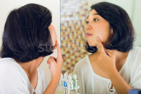 Asian woman discovering a pimple in face Stock photo © Kzenon