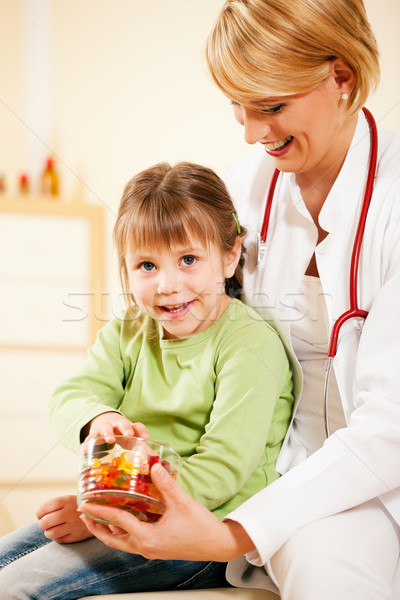 Pediatrician doctor giving candy to little patient Stock photo © Kzenon