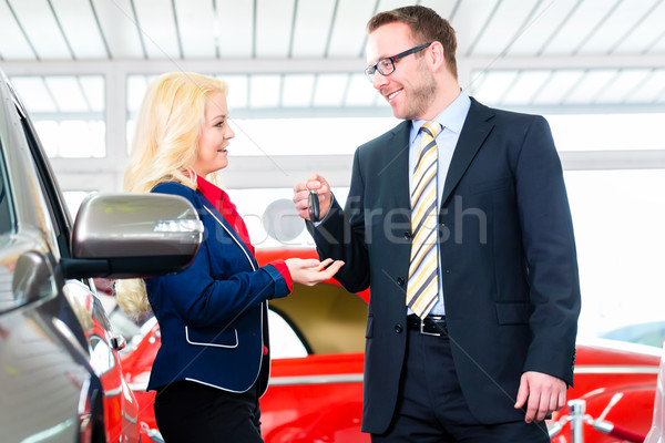 Woman with key to new auto in car dealership Stock photo © Kzenon