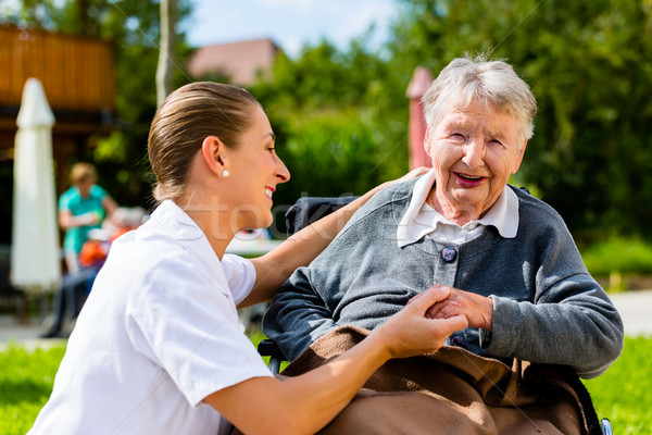 Nurse holding hands with senior woman in wheelchair Stock photo © Kzenon