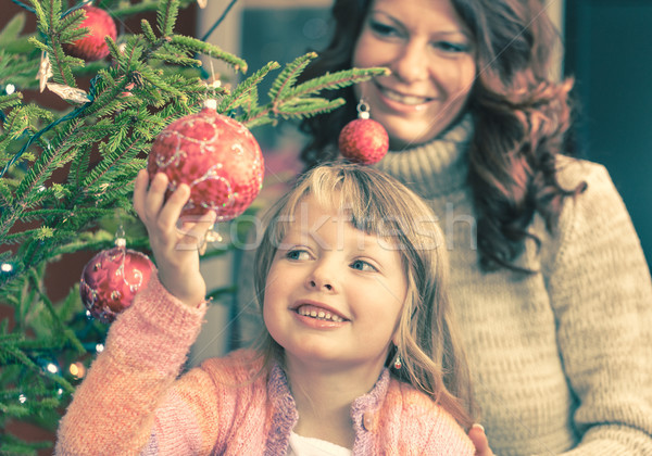 Stock photo: Young girl helping her mother decorating the Christmas tree