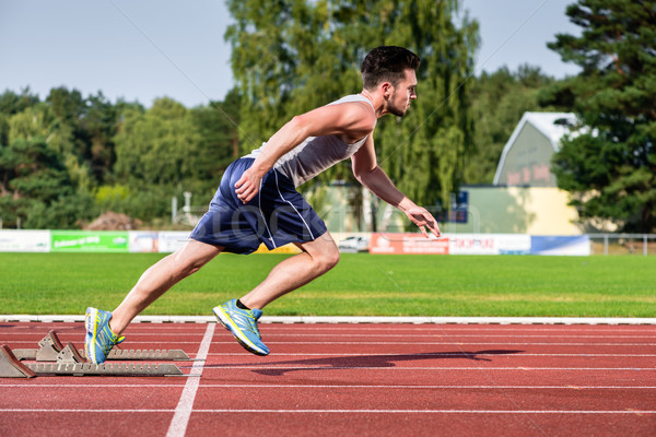 Athlete on cinder track of sports facility starts to sprint Stock photo © Kzenon