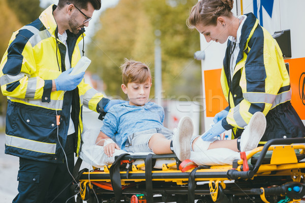 Medics putting injured boy on stretcher after accident Stock photo © Kzenon