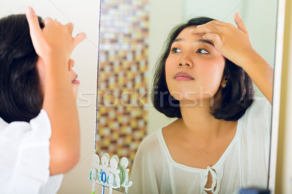 Asian woman discovering a pimple in face Stock photo © Kzenon