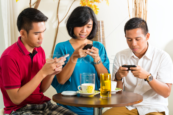 Asian people having fun with mobile phone Stock photo © Kzenon