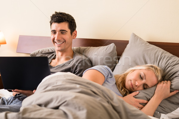 Young man using a laptop in bed at night Stock photo © Kzenon