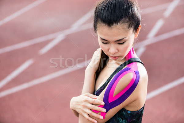 Woman taping with therapeutic tape on cinder track Stock photo © Kzenon