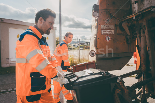 Garbage man and women cleaning dustbins into waste truck Stock photo © Kzenon