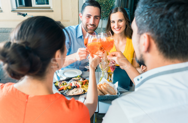 Four friends toasting together with a cold refreshing alcoholic drink Stock photo © Kzenon