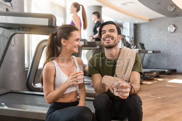 Cheerful young man and woman drinking plain water during break at the fitness Stock photo © Kzenon