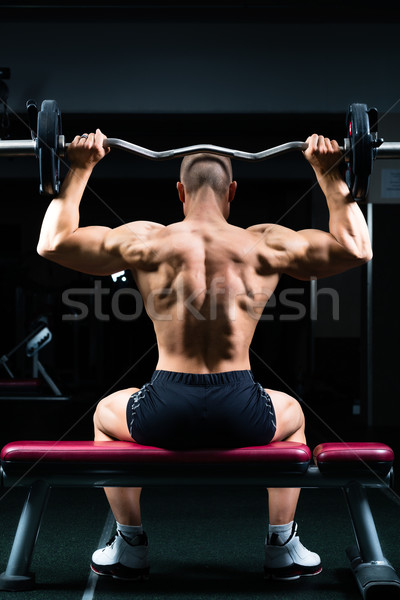 Man in gym or fitness studio on weight bench Stock photo © Kzenon