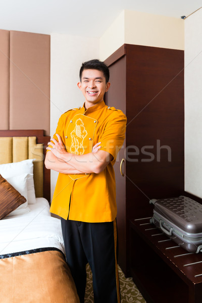 Asian Chinese porter bringing suitcase to luxury hotel room Stock photo © Kzenon