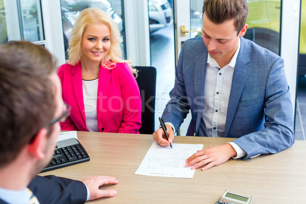 Man signing sales contract for auto at car dealership  Stock photo © Kzenon