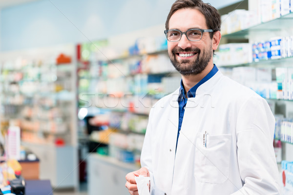 Apothecary in pharmacy standing at shelf with drugs Stock photo © Kzenon