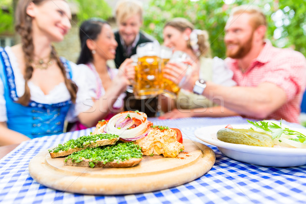 Friends in beer garden with drink and Bavarian appetizers Stock photo © Kzenon