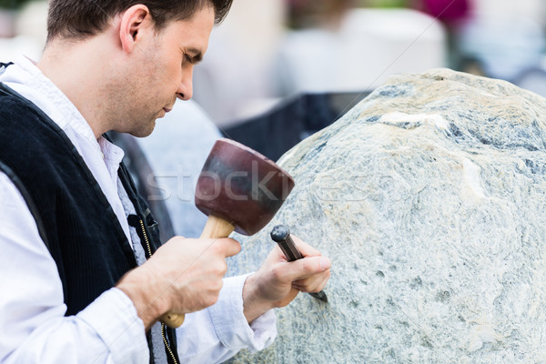 Sculptor with mallet and cutter working on erratic block Stock photo © Kzenon