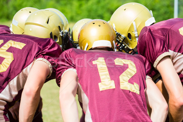 Stock photo: American Football players at strategy huddle