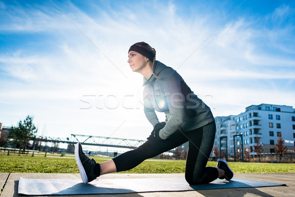Határozott fiatal nő nyújtás láb térdel kilátás Stock fotó © Kzenon