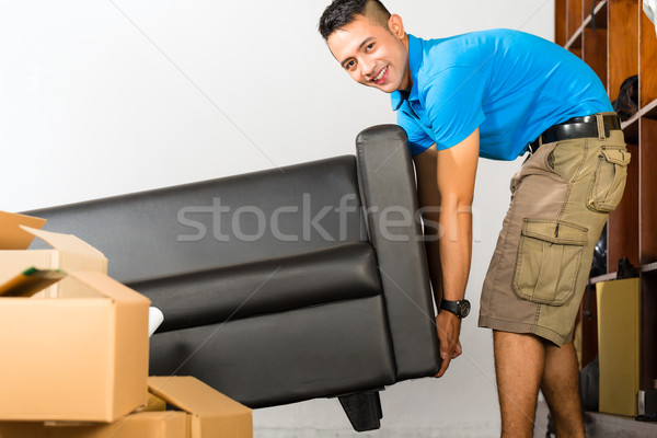 Young asian man lifting a couch Stock photo © Kzenon