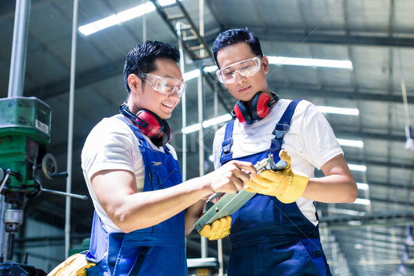 Stock photo: Two industrial workers inspecting work piece