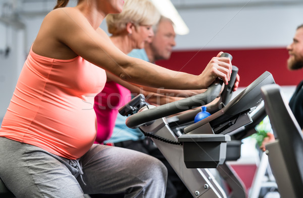 Pregnant woman spinning on fitness bike in the gym Stock photo © Kzenon