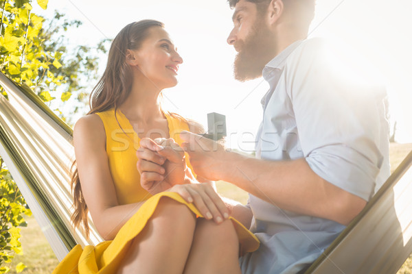 Young man making marriage proposal to beautiful girlfriend while Stock photo © Kzenon