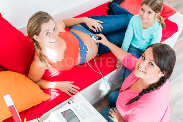 Young girl watching midwife attaching CTG to pregnant belly Stock photo © Kzenon