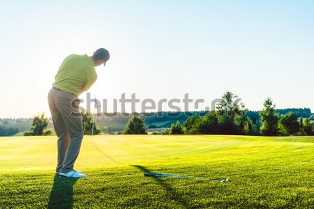 Experienced male golfer hitting the golf ball towards the cup Stock photo © Kzenon