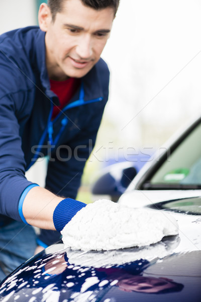 Hard-working man polishing car with white microfiber mitt Stock photo © Kzenon