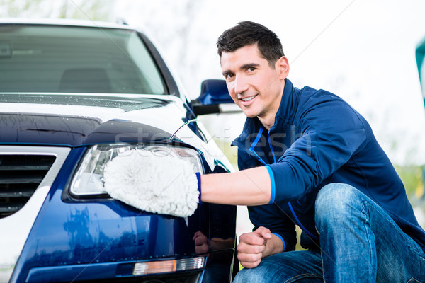 Smiling man cleaning the headlamp on his car Stock photo © Kzenon