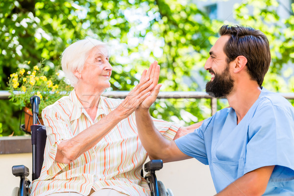 Senior woman and nurse giving High five in nursery home Stock photo © Kzenon