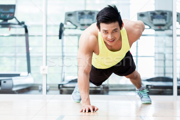 Muscular young man doing one armed pushups in gym Stock photo © Kzenon