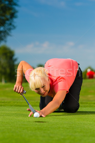 Stock photo: Young female golf player on course aiming for put