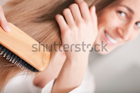 Stock photo: Young woman brushing her hair 