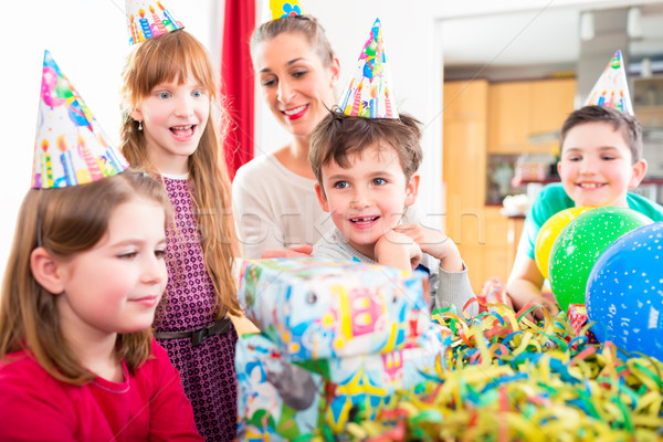 Child unwrapping birthday gift with friends Stock photo © Kzenon