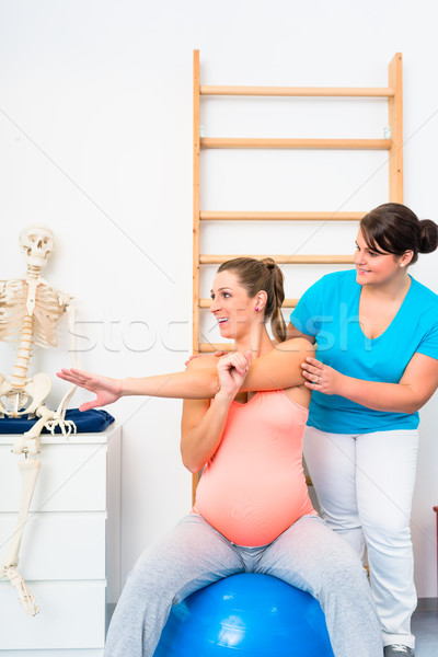 Pregnant woman does stretching exercises with physical therapist Stock photo © Kzenon