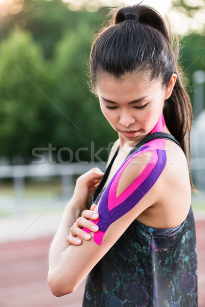 Woman taping with therapeutic tape on cinder track of sports sta Stock photo © Kzenon