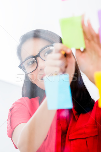 Young employee looking at multiple reminders while planning her work Stock photo © Kzenon