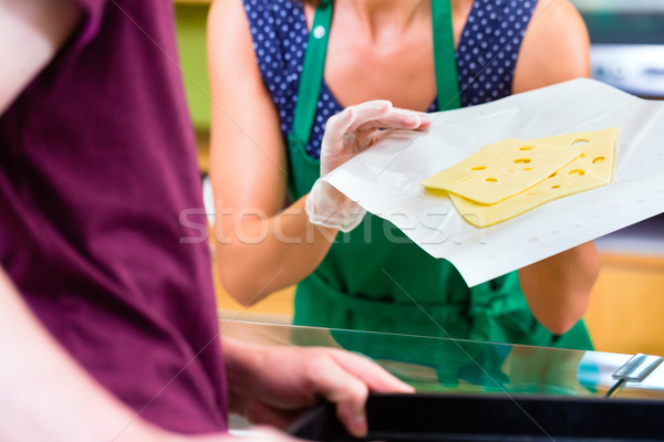 Saleswoman at counter offering cheese Stock photo © Kzenon