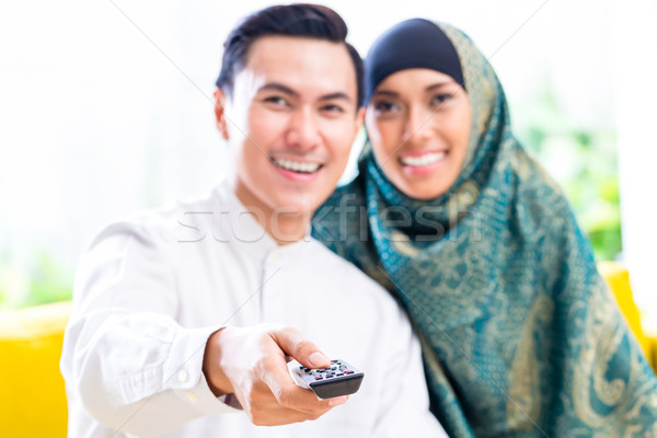 Asian Muslim Couple switching TV with remote control Stock photo © Kzenon